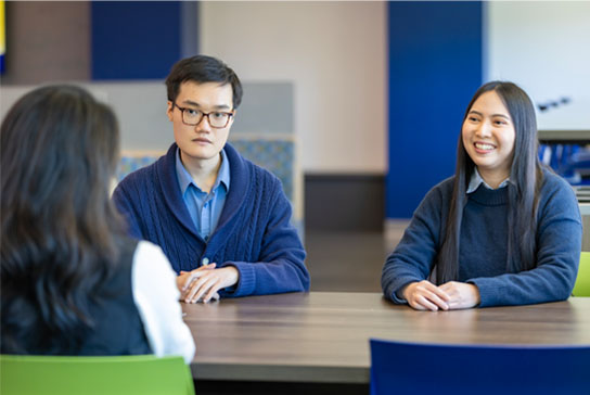 People sitting at a desk talking together.